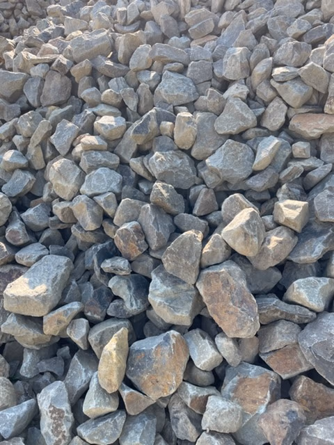 Pile of gray and brown irregular rocks stacked together, like crushed stone or gravel